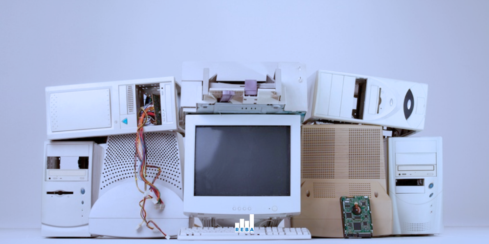 A collection of vintage desktop computer towers, a CRT monitor, an old printer, and exposed computer parts arranged against a plain background.