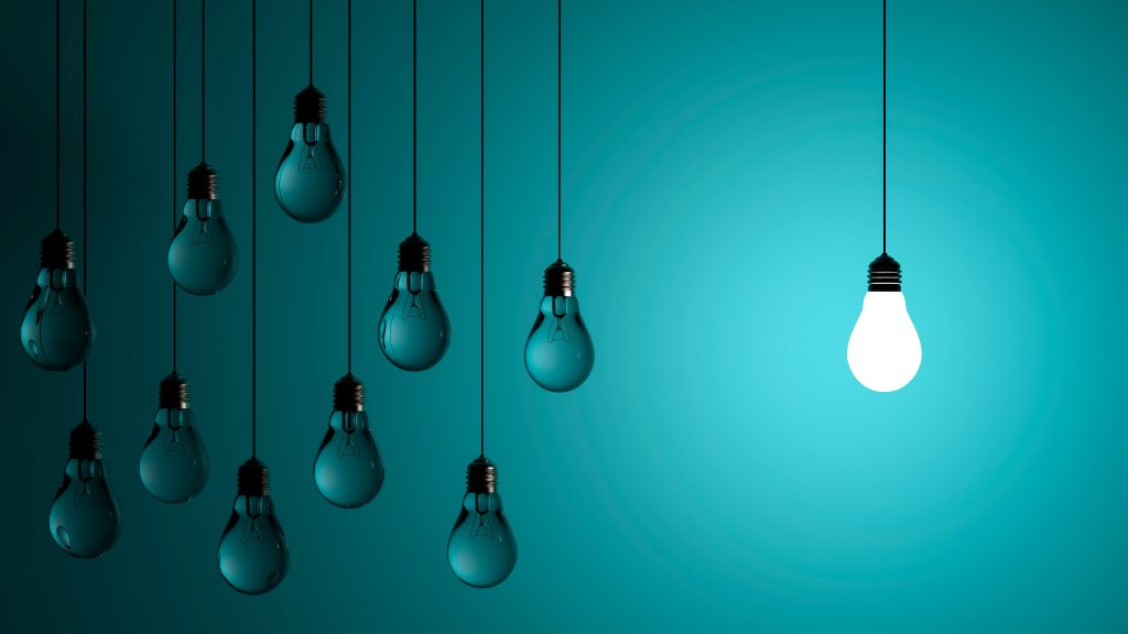 Nine hanging lightbulbs are shown against a teal background; eight are unlit and one on the right is brightly glowing, casting light in the scene.